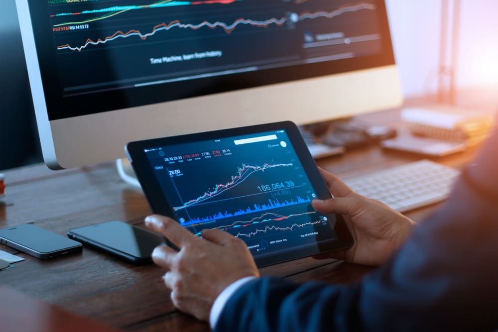 BusinessmanCheckingStockMarketOnDigitalTabletAndADesktop
