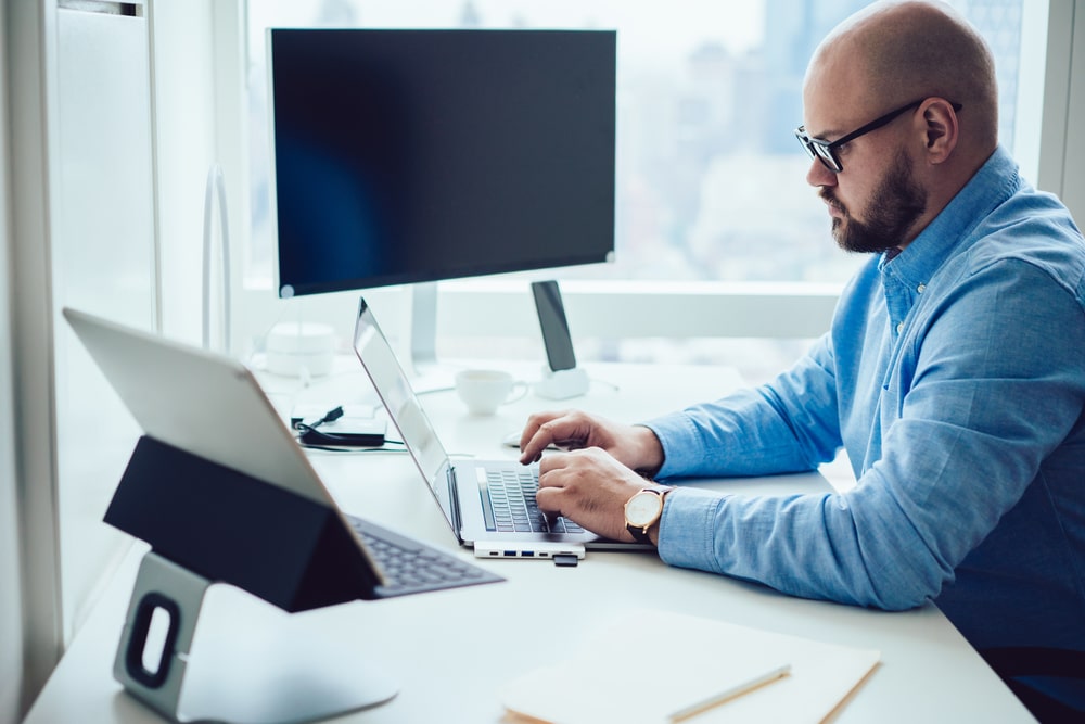 SideViewOfConcentratedBeardedMaleEmployeeInFormalWear